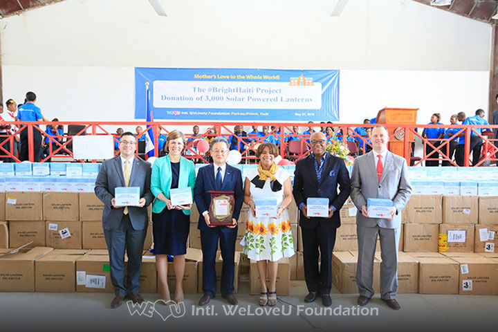 WeLoveU and Haiti vocational school representatives hold solar-powered lanterns