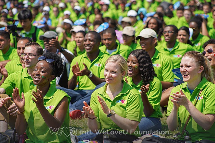A snapshot of walkathon participants sitting on the grass in front of the stage.