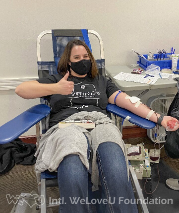 A donor gives a thumbs up while donating blood