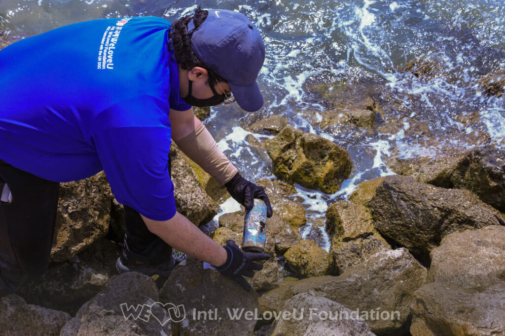 A volunteer picks up a rusted metal can from the beach trail in Tampa