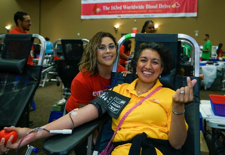 A happy blood donor from the WeLoveU Foundation is pictured with a blood center employee