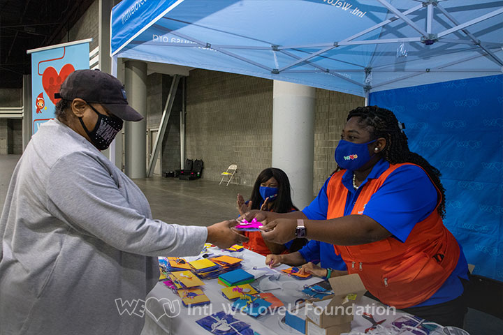 WeLoveU volunteers hand a gift to a blood drive participant