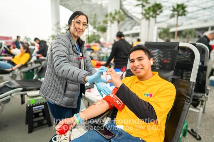 Blood center staff and a WeLoveU volunteer make a heart with their hands