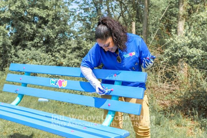 A volunteer painting a bench