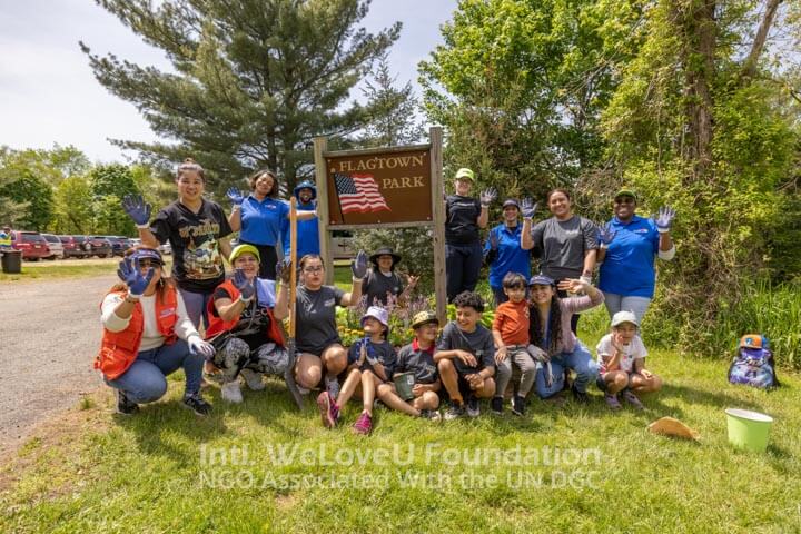 Volunteers sitting around Flagtown Park sign with freshly planted flowers